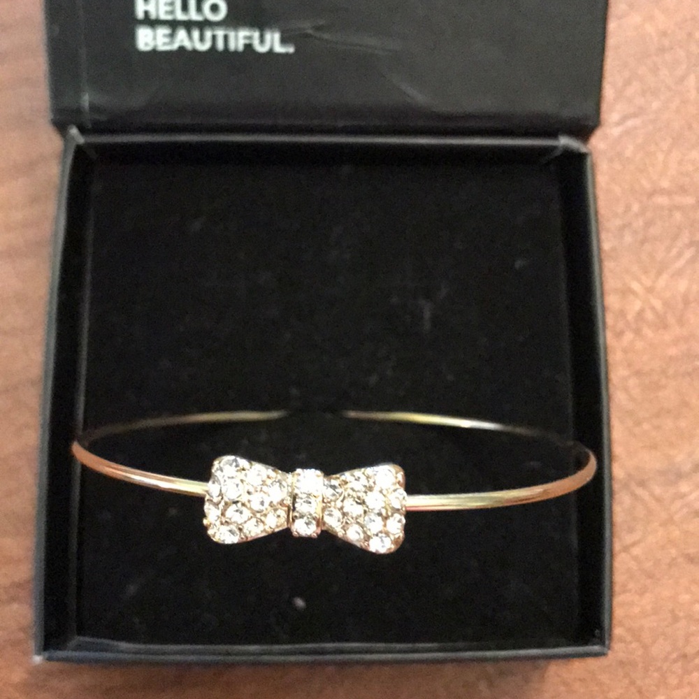 Bangle bracelet w/ rhinestone bow in gold tone.